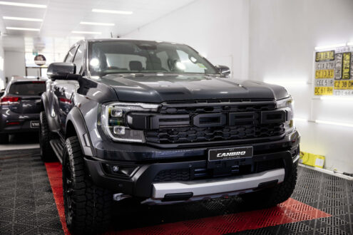 Black Ford Ranger Raptor parked in a garage, showcasing a gleaming finish with a nearly invisible coat of paint protection film (PPF) applied for off-road adventure protection.